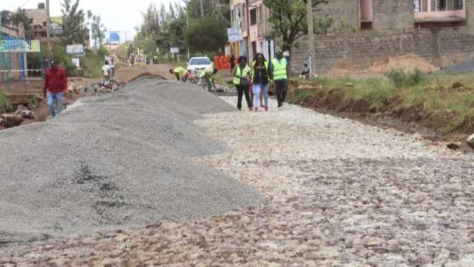 A heavy construction excavator and a grader on a dirt road, symbolizing the start of reconstruction work on the 27-kilometre Rainbow-Juja Farm Road project in Ruiru, Kenya.