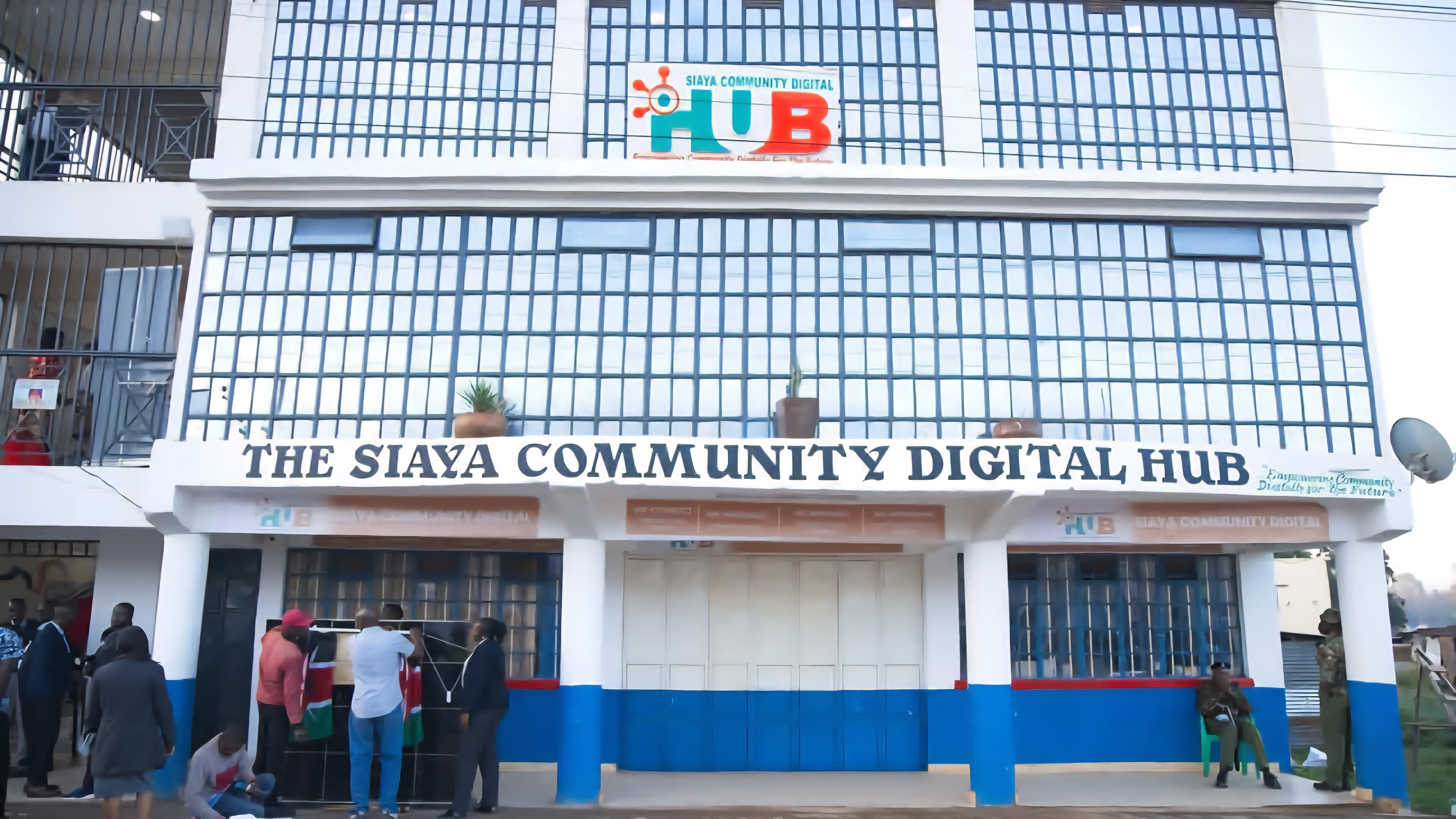 A medium-shot photo of the multi-storey Siaya Community Digital Hub, featuring a glass-fronted exterior and a sign reading Dr Oburu Odinga Plaza.