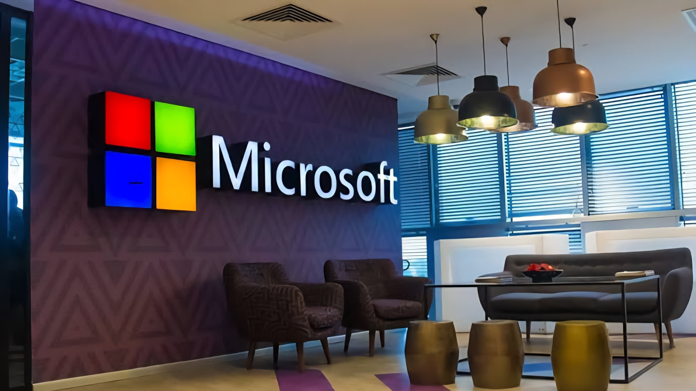 Interior view of a modern glass and steel Microsoft corporate building with a large colorful logo mounted on a dark facade.