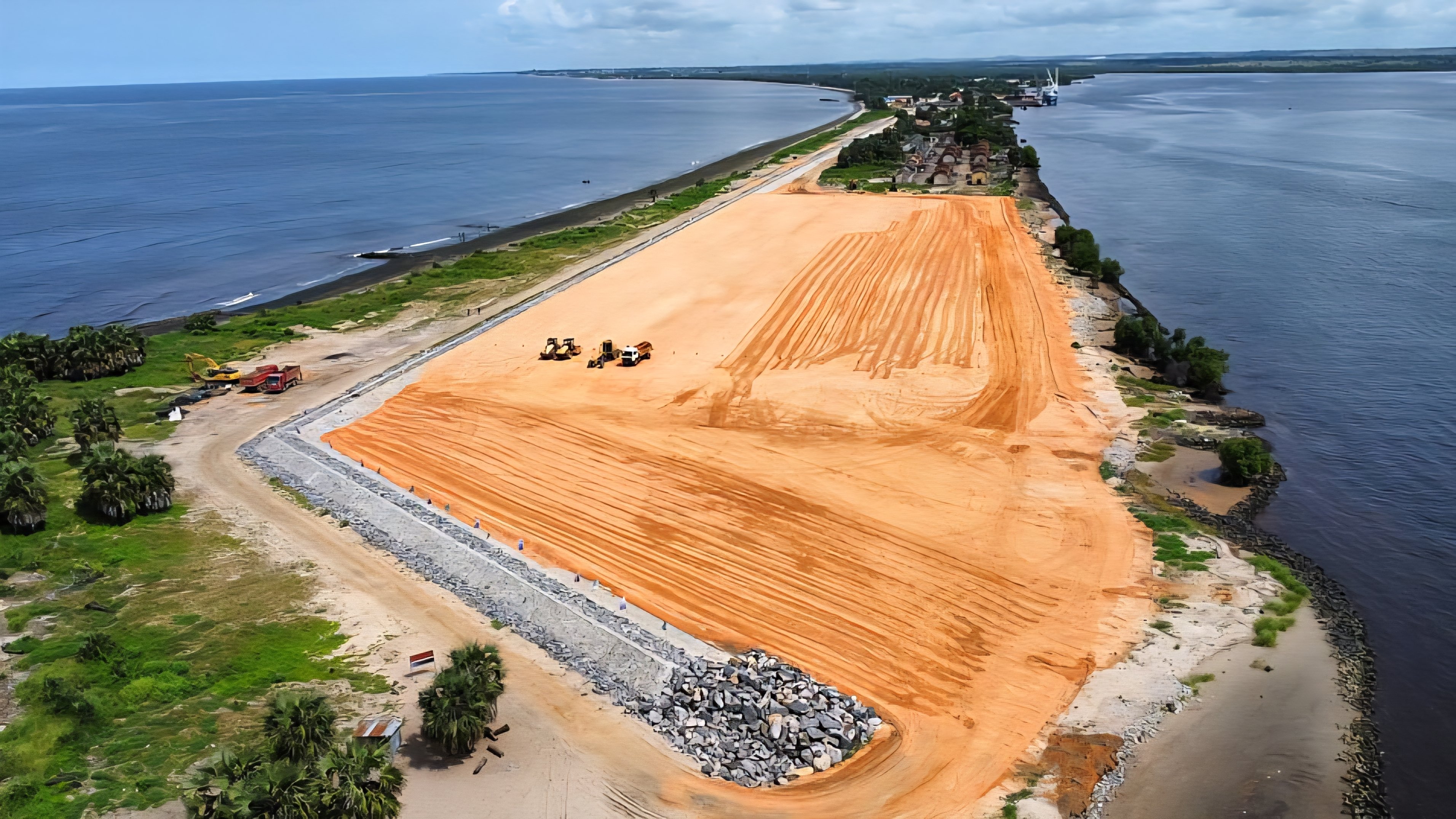 Aerial view of the early construction site at the Banana Port location on the Atlantic coast of the Democratic Republic of Congo, showing cleared land and heavy machinery.