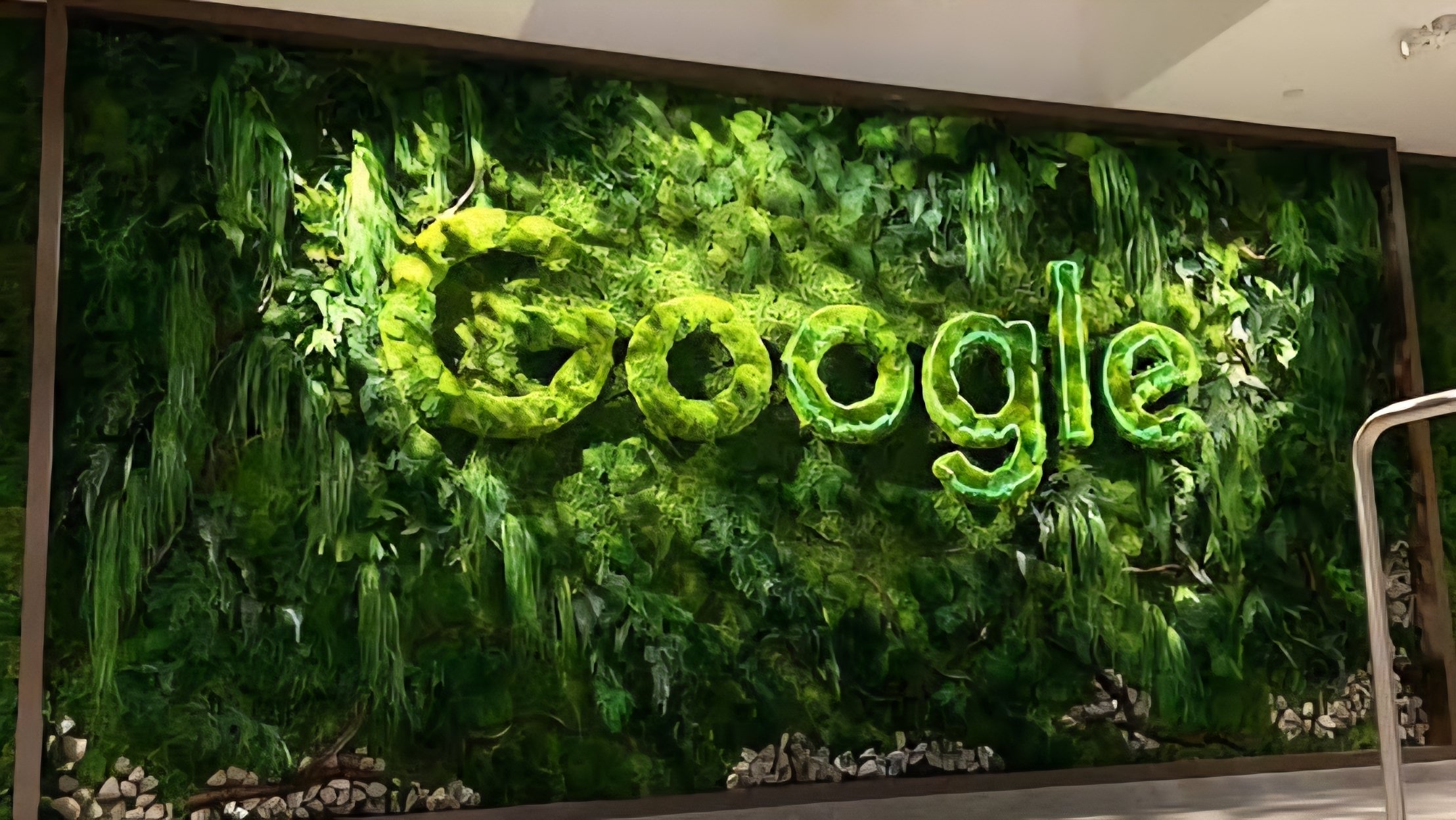 Large 3D Google logo installed in a modern office lobby with indoor plants and wooden flooring.