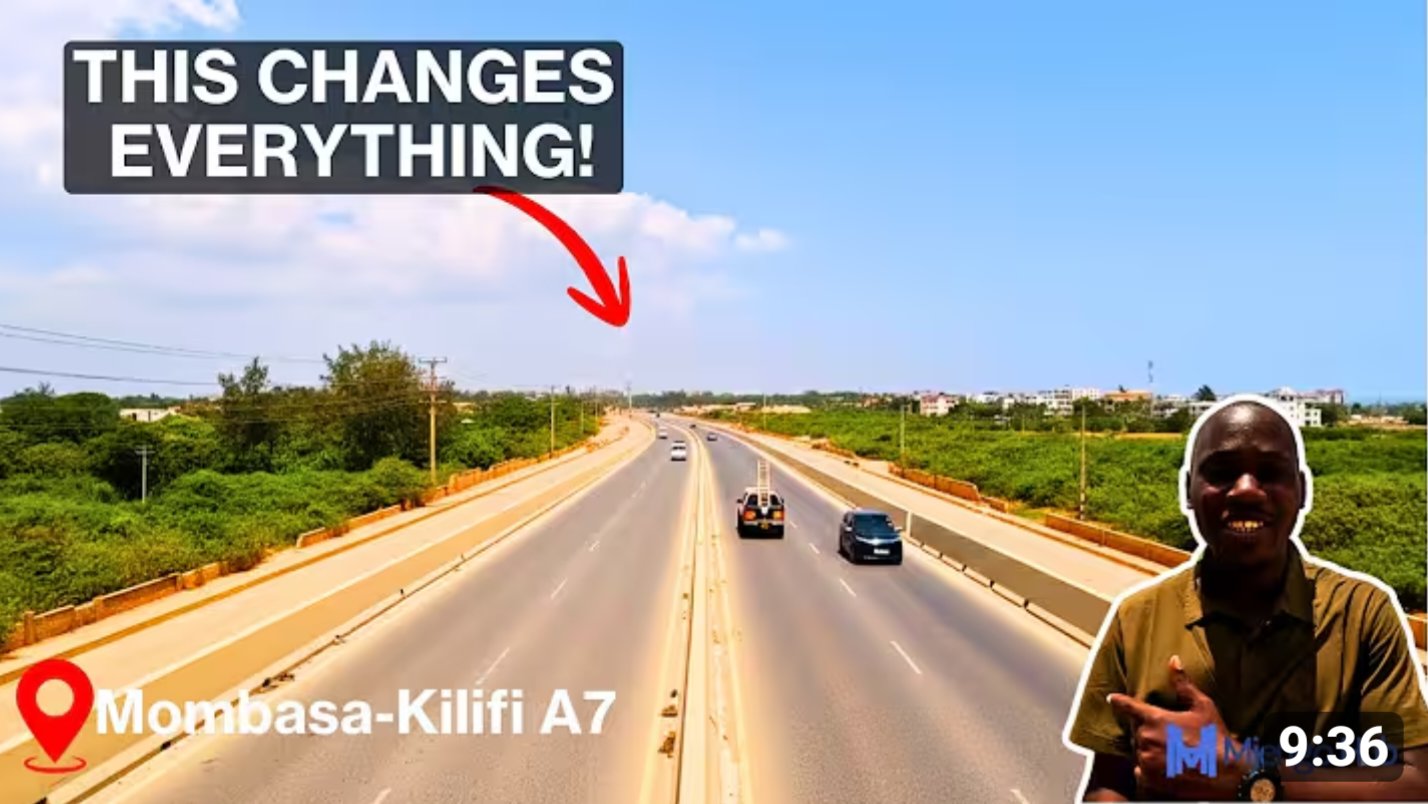 Aerial view of the dualled A7 highway section showing new asphalt lanes and construction activity near the coastal creek.