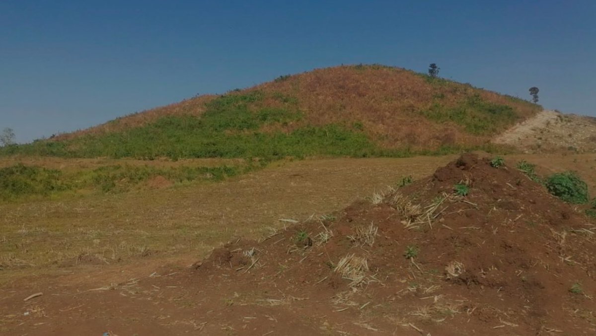 A wide-angle landscape shot showing the cleared red soil of the Got Alila hill terrain where the early phase of the Soin-Koru multipurpose dam project began.