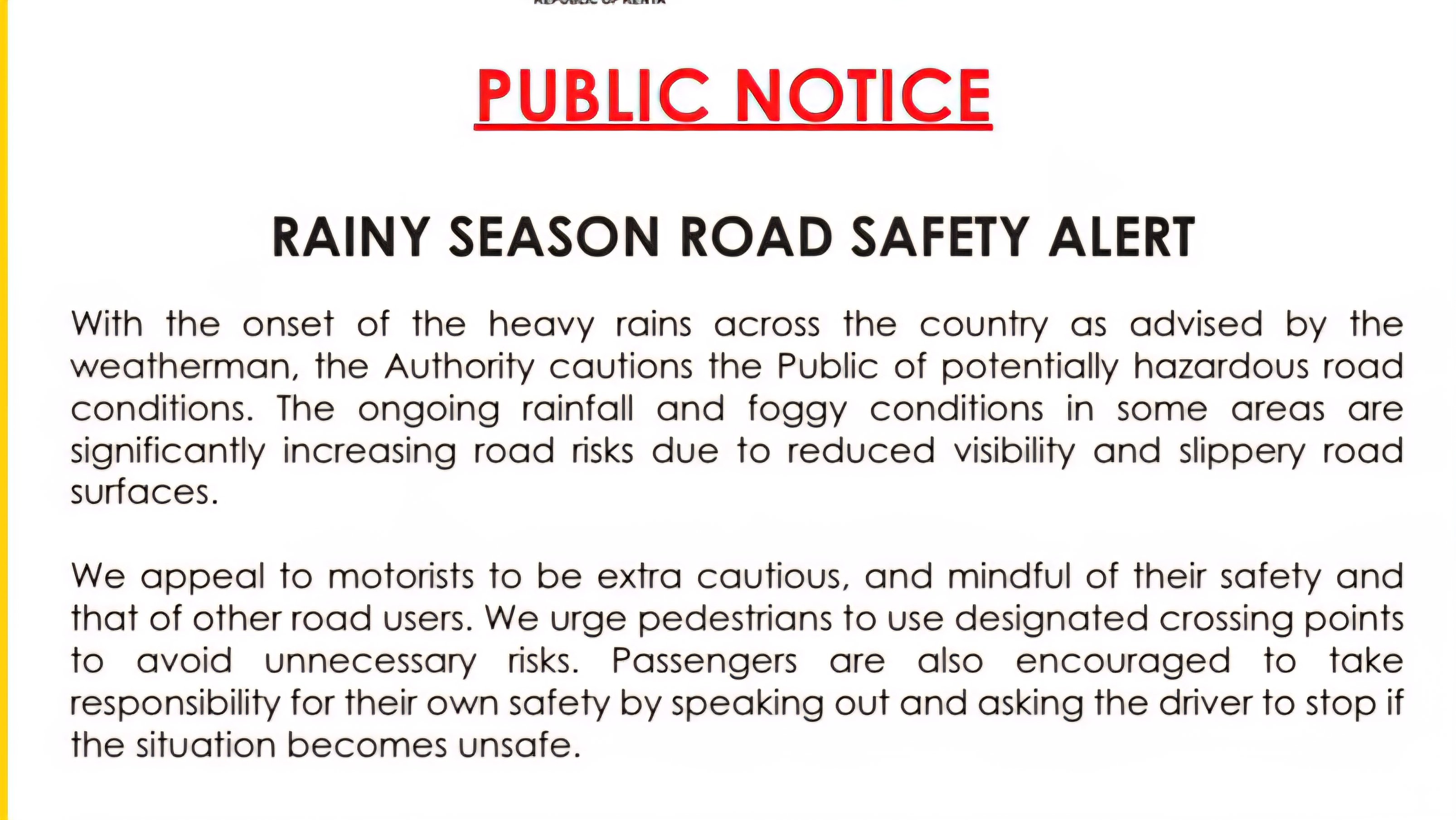 A vehicle driving through heavy rain on a paved Kenyan highway with headlights on and visible water spray from the tires.