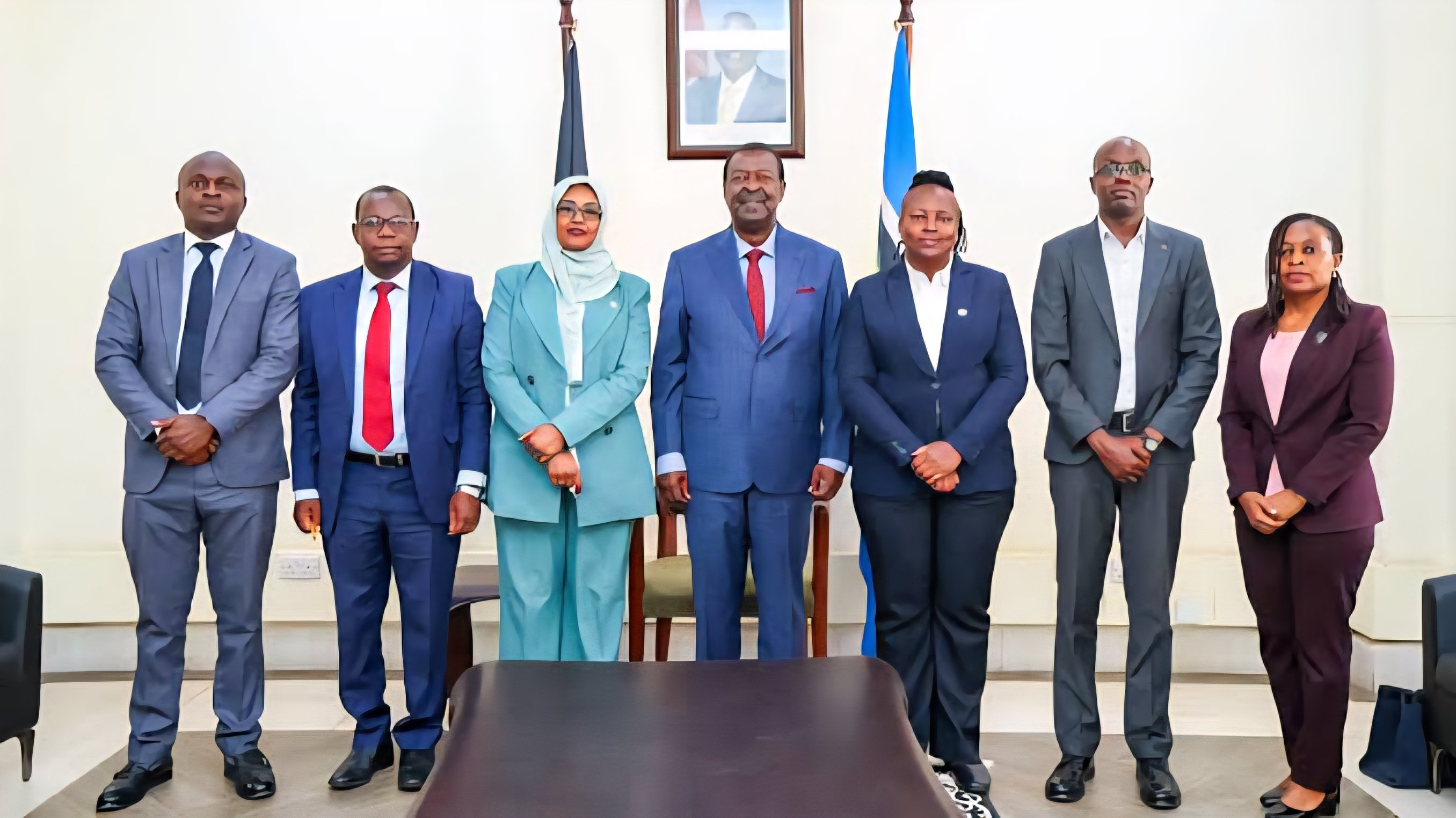 Musalia Mudavadi and another official standing in front of a framed announcement about the new African Union campus project in Nairobi.