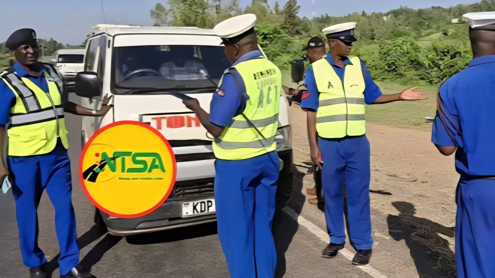 A police officer and NTSA enforcement officers conduct a joint traffic check along a major highway in Kenya.