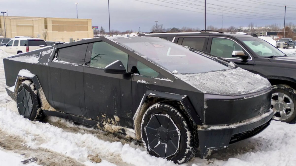 A Tesla Cybertruck coated in snow and ice sits parked in a winter lot, illustrating electric vehicle performance considerations in cold climates.