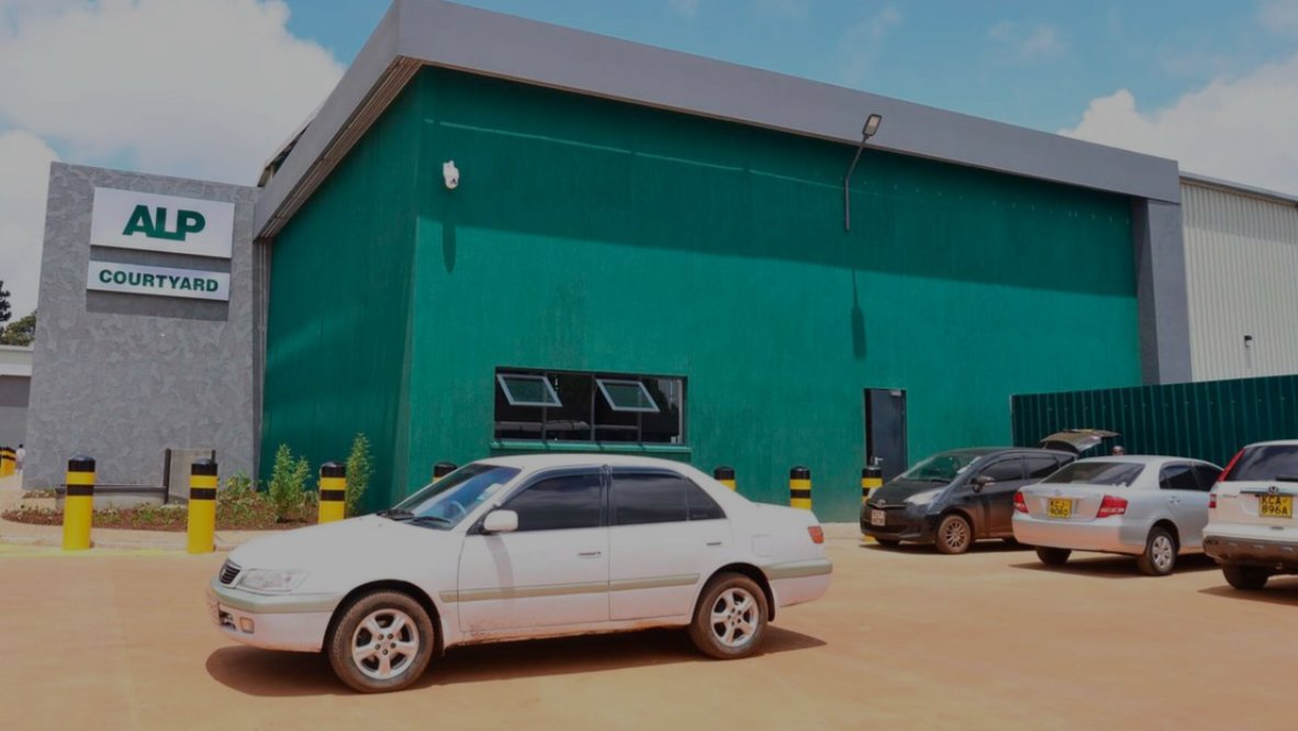 Front view of the green ALP Courtyard industrial warehouse facility with parked vehicles in Kenya.