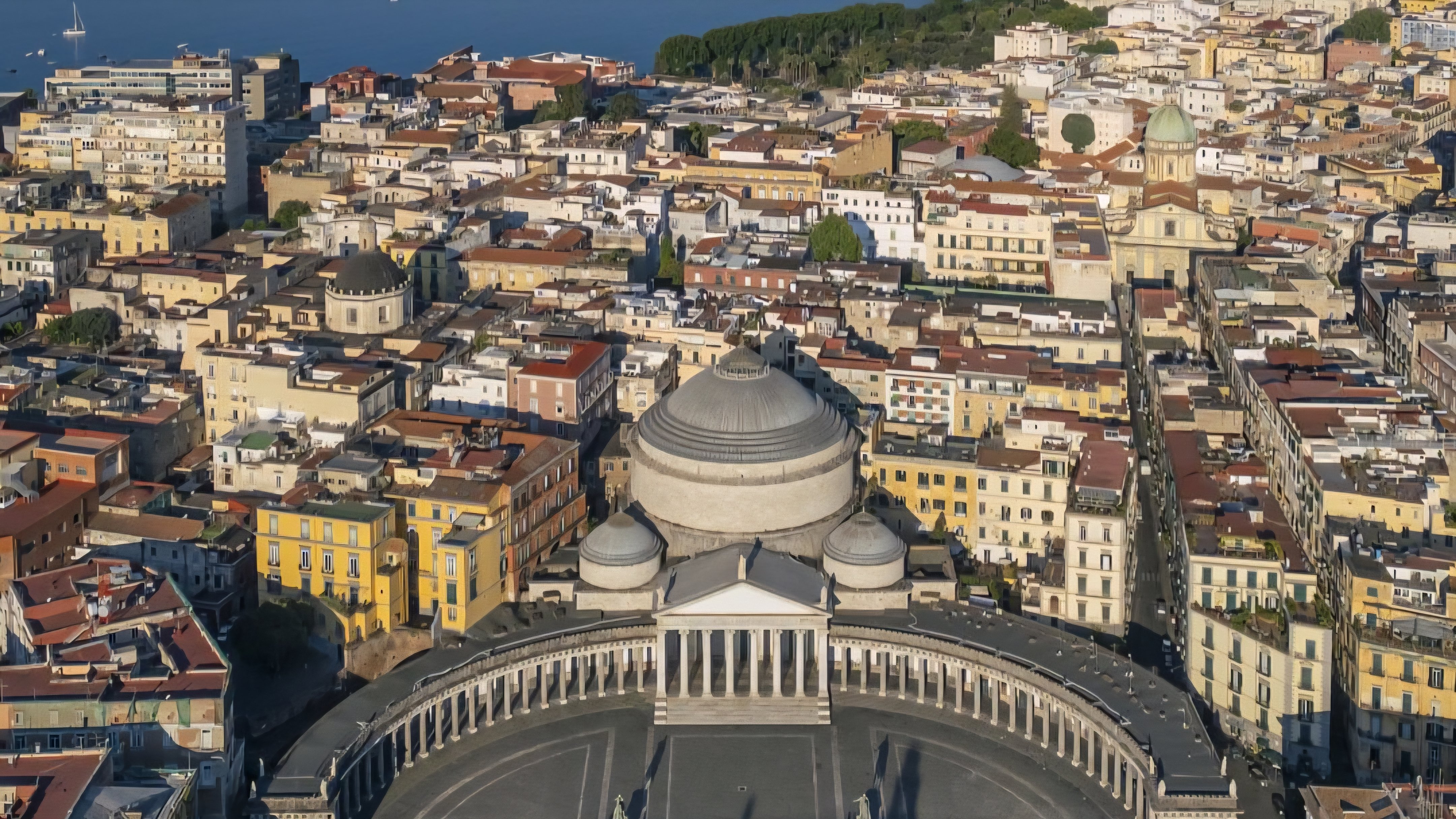Aerial view of the historic architecture and urban layout of Naples, Italy, highlighting the city center and surrounding coastal development.