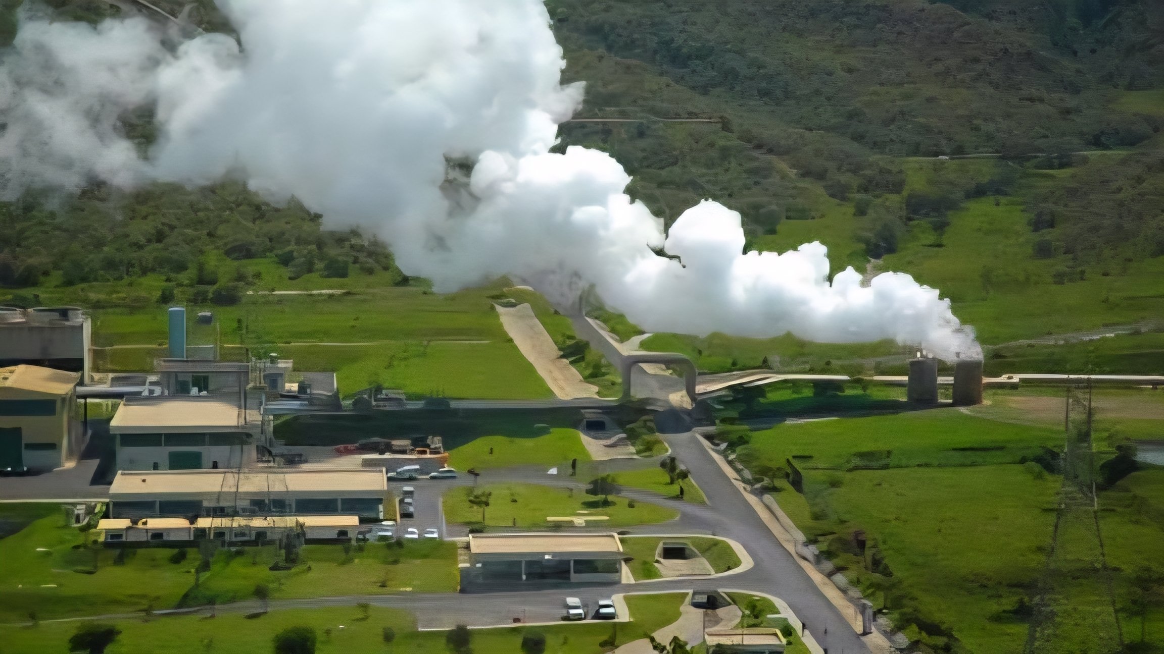 An aerial view of a geothermal power plant in the Rift Valley featuring steam pipes and cooling towers.