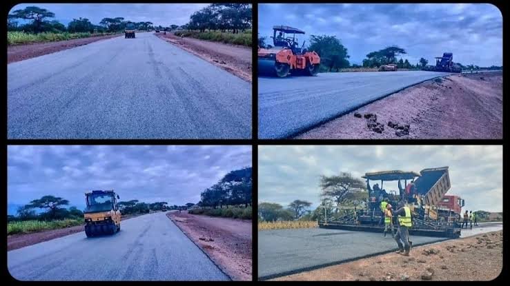 A newly paved asphalt highway in rural Kenya extending toward the horizon under a cloudy sky.