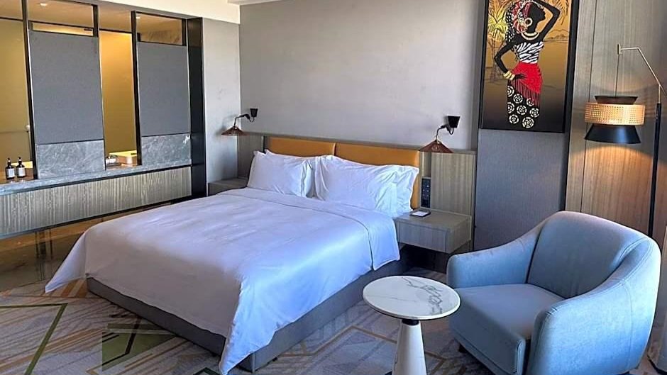 Hotel bedroom with a neatly arranged bed, modern furnishings and comfortable guest accommodation.