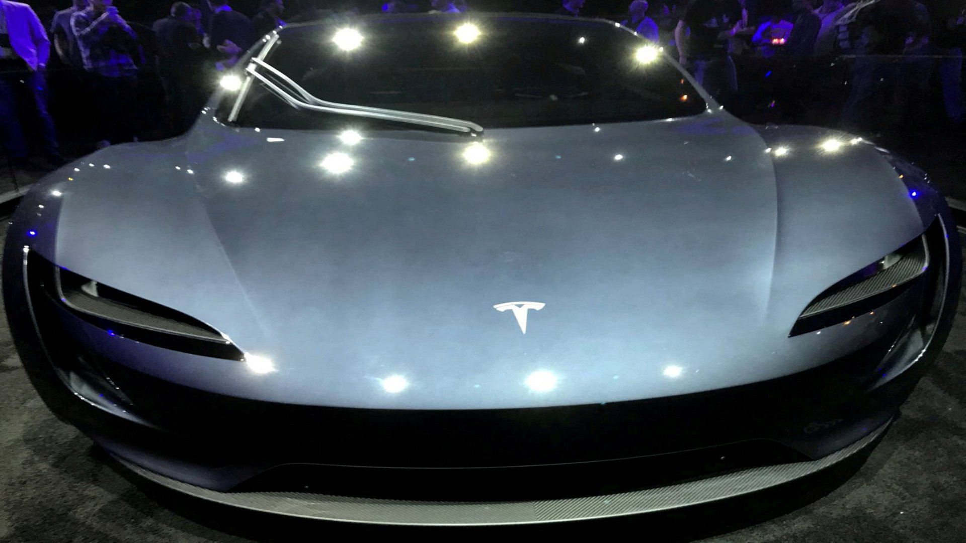 A sleek Tesla high-speed electric sports car displayed on a modern vehicle stage.
