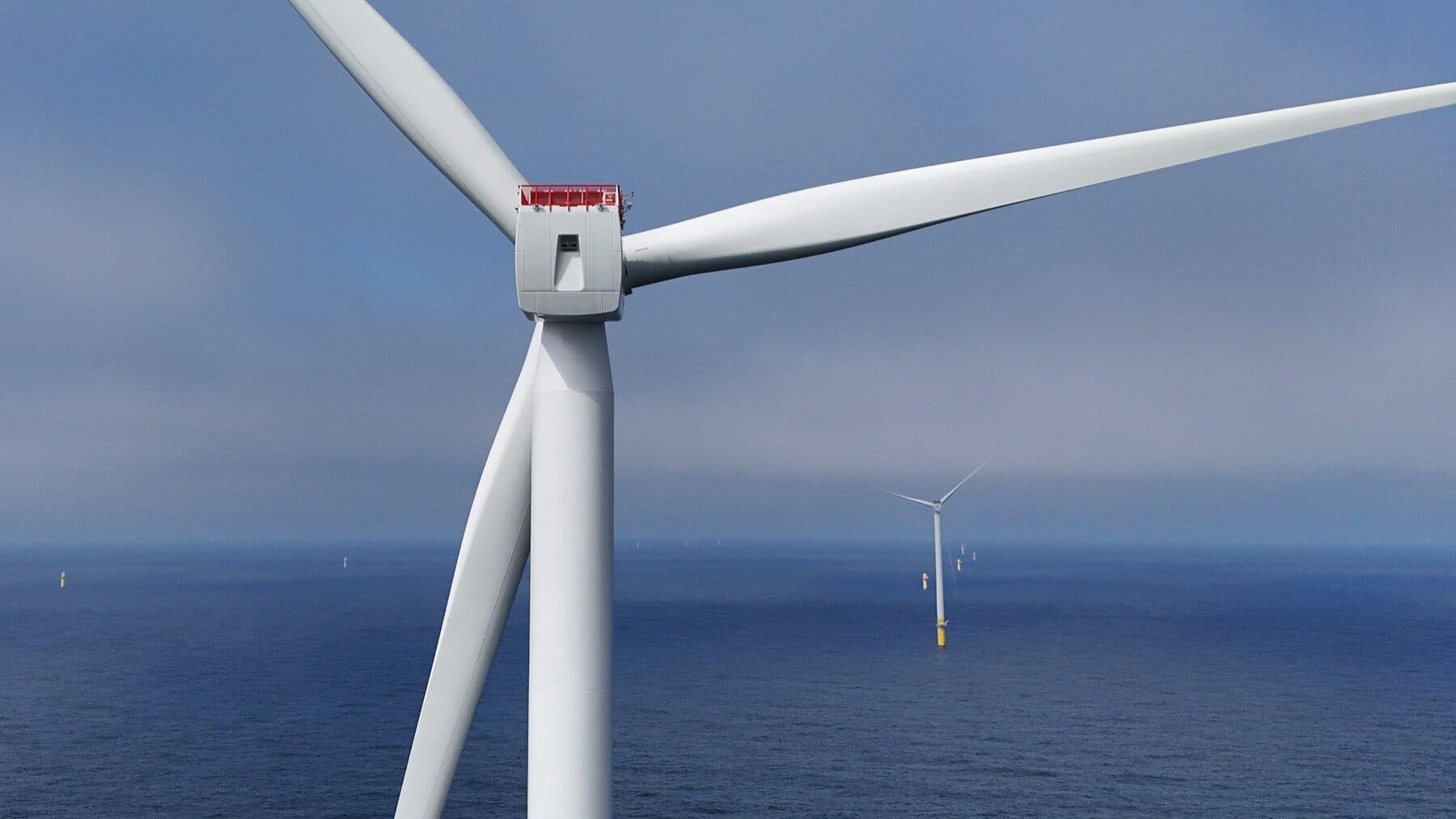 An offshore wind turbine installed in ocean waters against a blue sky.