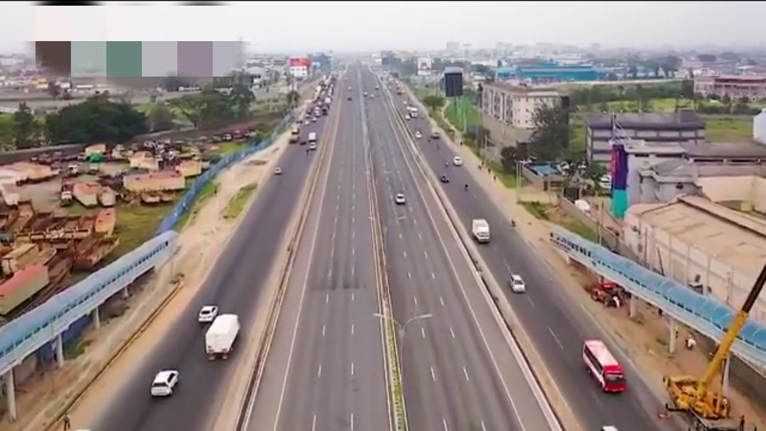 Aerial view of a modern elevated expressway cutting through an urban landscape with vehicles moving in both directions