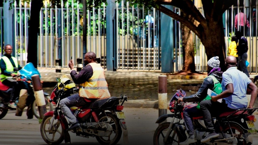 Commercial motorcycle riders, known as boda bodas, navigating traffic on a Nairobi street