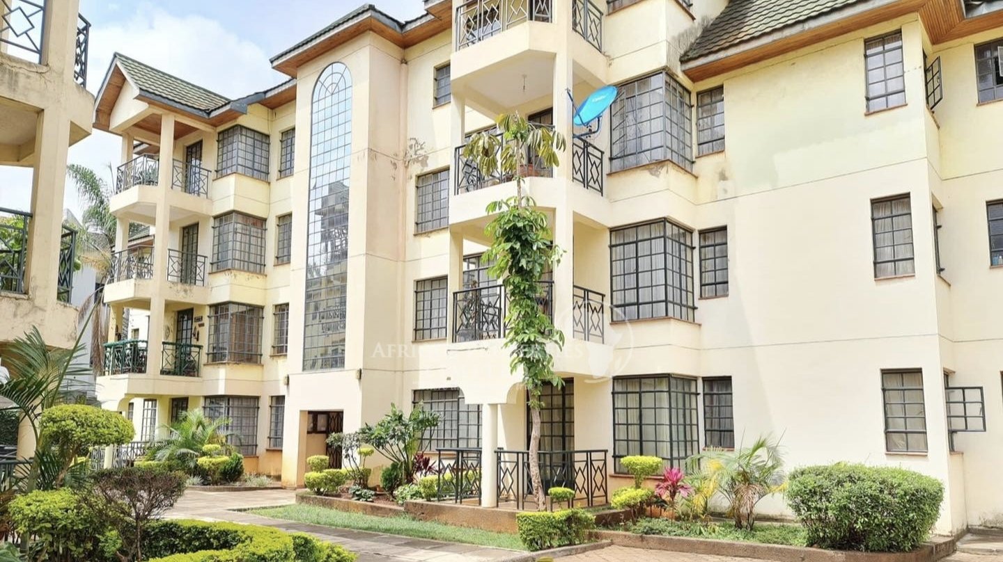 A modern mid-rise residential apartment development in Nairobi's Kilimani neighbourhood, surrounded by mature trees and a perimeter fence.