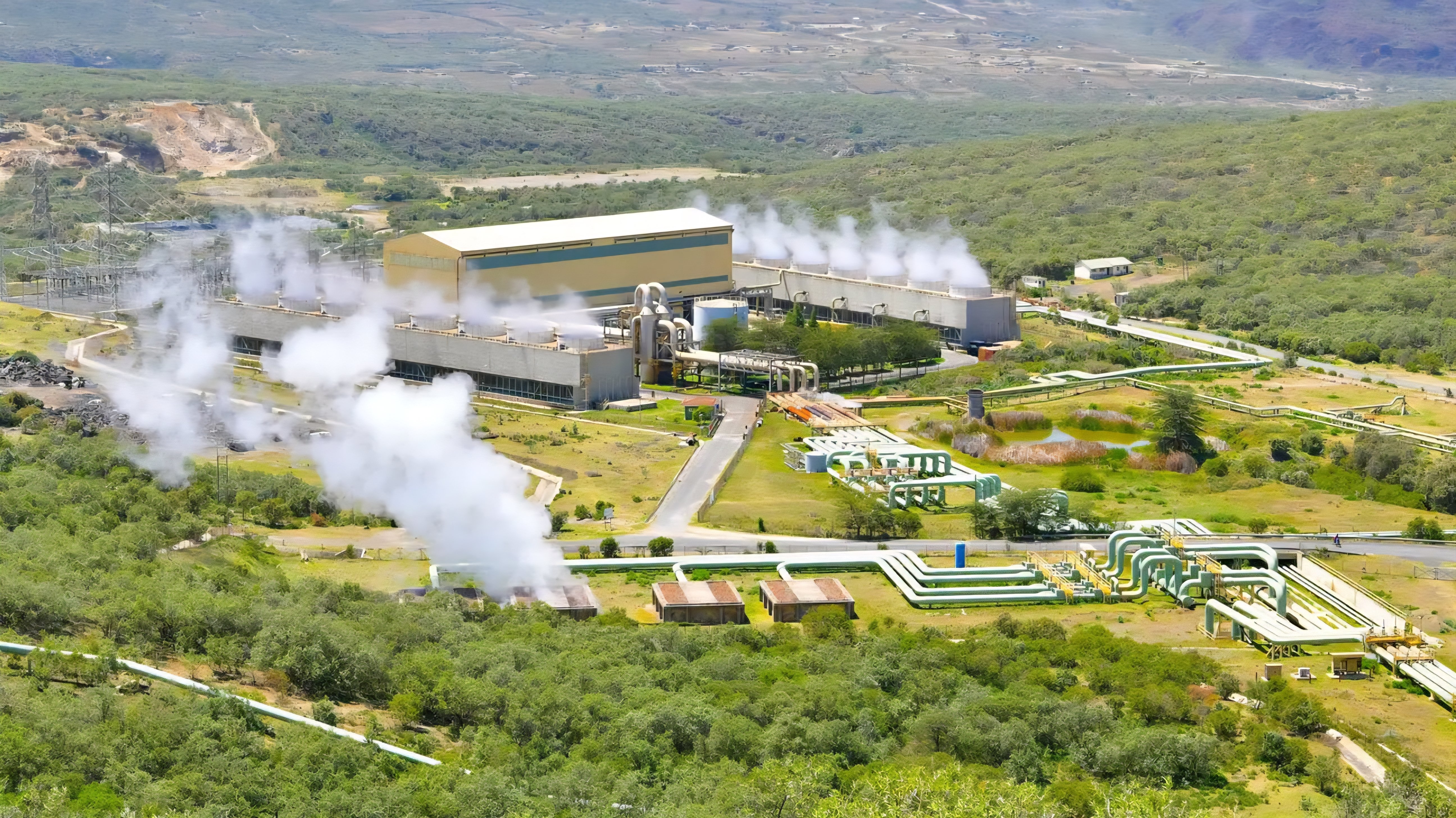 Aerial view of the Olkaria geothermal power station in Kenya showing steam rising from cooling towers against the green landscape of the Great Rift Valley.