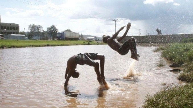 Two people swimming in the clear waters of Lake Nakuru surrounded by scenic landscapes