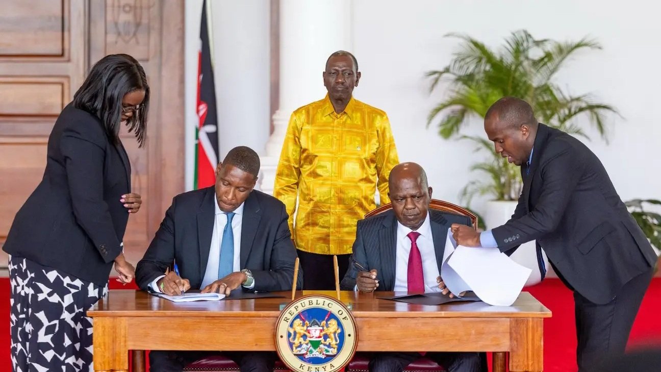 President William Ruto, officials from Zaria Group, and Kenya Railways representatives signing a lease agreement at a wooden desk in State House.