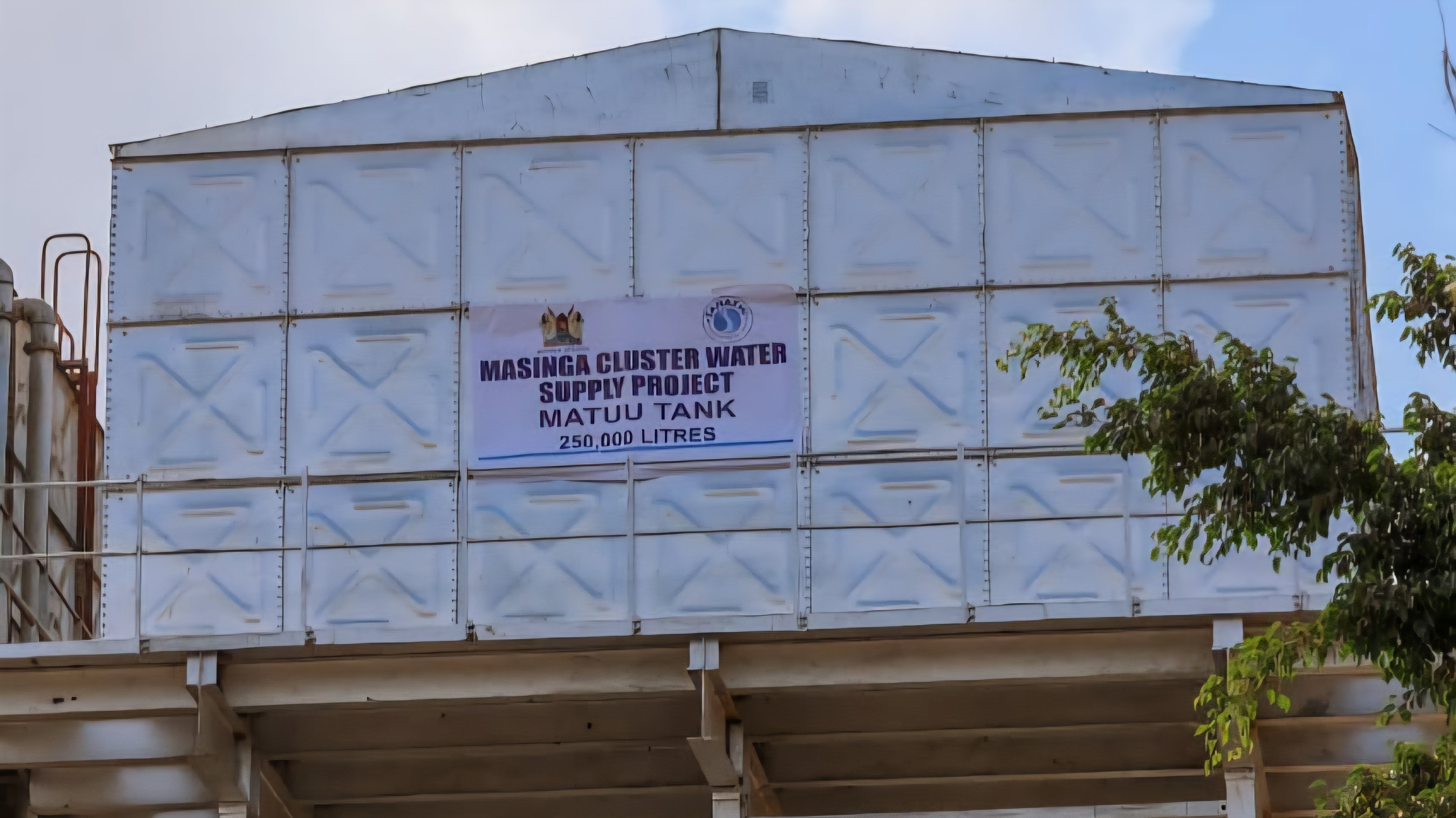 An elevated white modular steel water storage tank bearing a project sign, referenced as 265467.jpg.