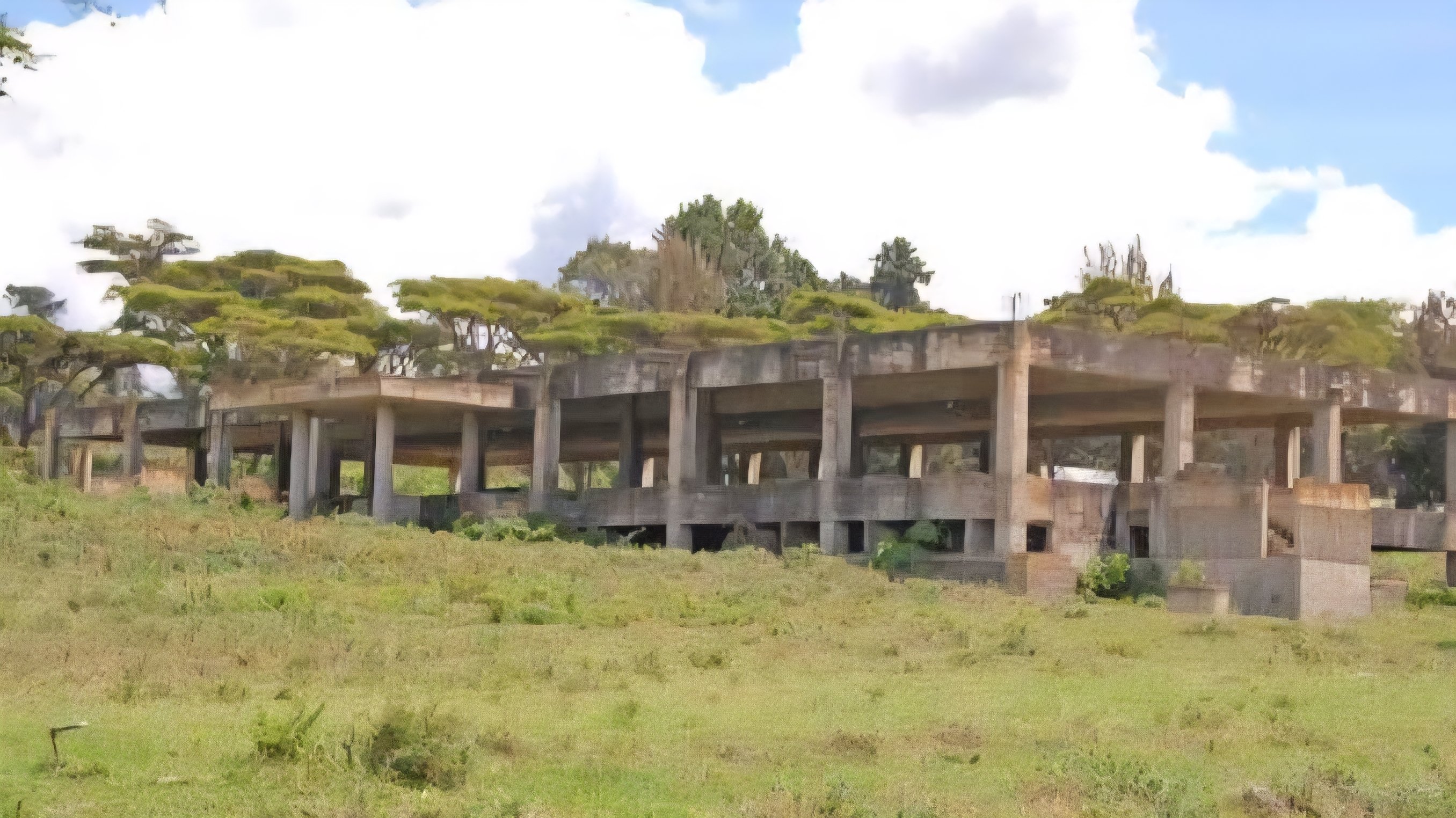 An unfinished multi-storey concrete building structure at a Kenyan university campus with exposed reinforcement bars and no active workers.