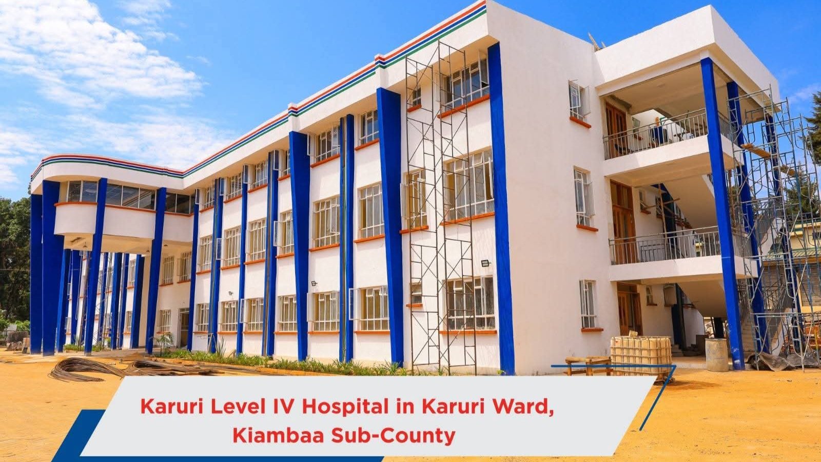 A multi-storey concrete hospital building with scaffolding and a perimeter fence in Kiambu County.