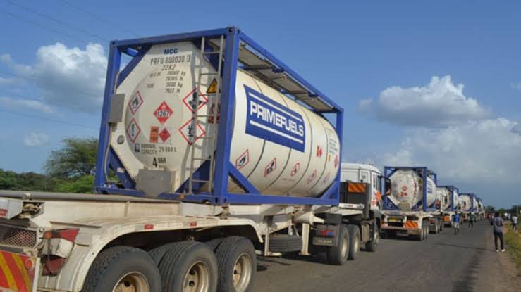 A row of heavy-duty fuel tanker trucks parked at a modern industrial petroleum loading terminal in Kenya.