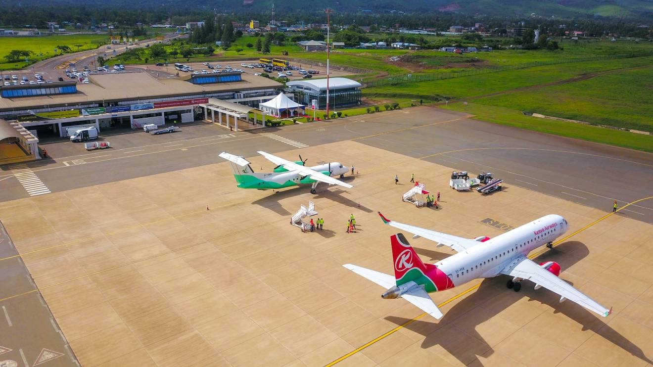 A modern urban cityscape of Kisumu, Kenya, featuring wide, clean pedestrian walkways (NMT corridors) flanked by green trees, symbolizing its status as a clean, orderly, and well-managed economic hub.