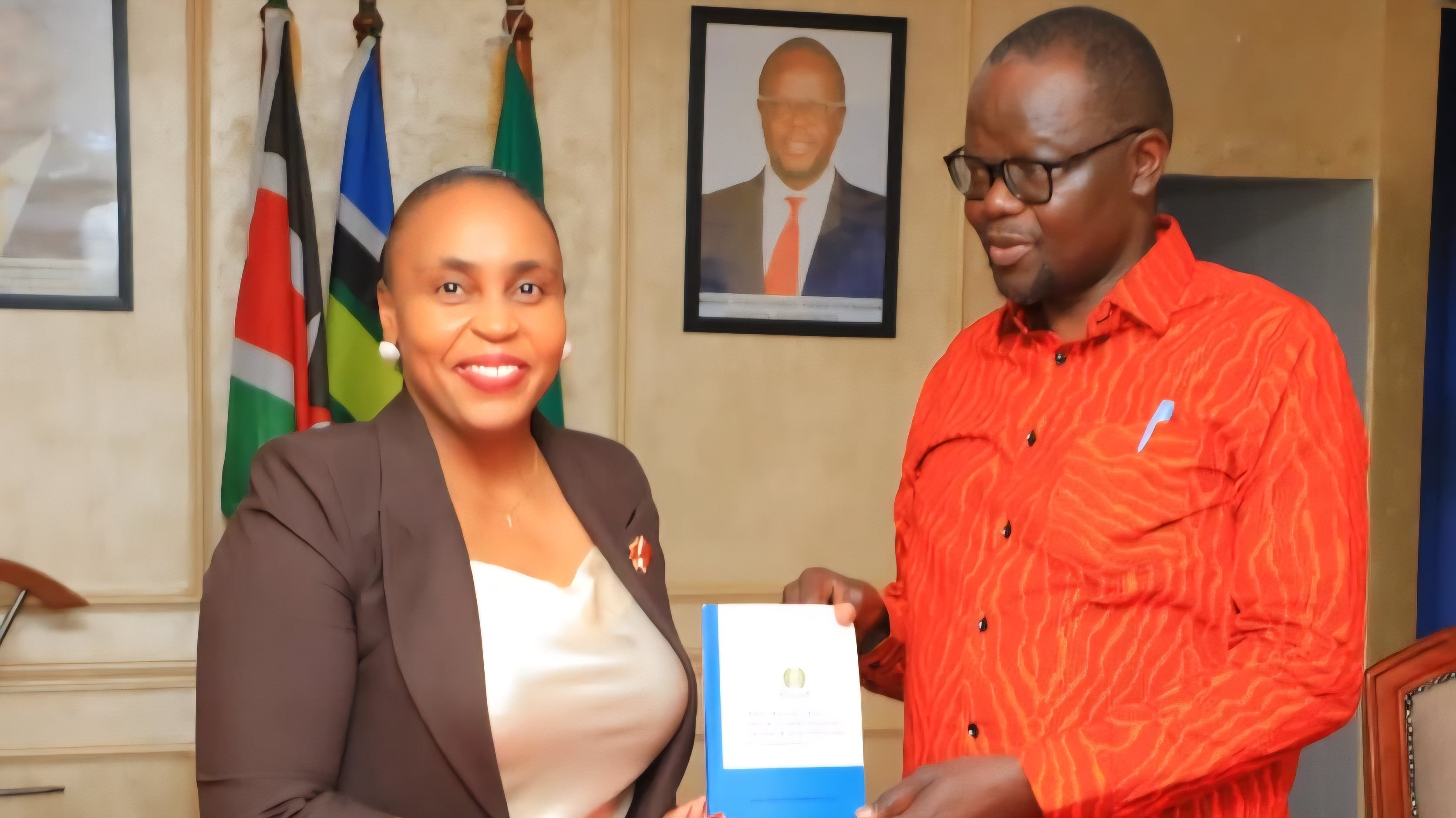 Principal Secretary Dr. Caroline Karugu and Migori Governor Ochilo Ayacko holding a document during a meeting on border trade.
