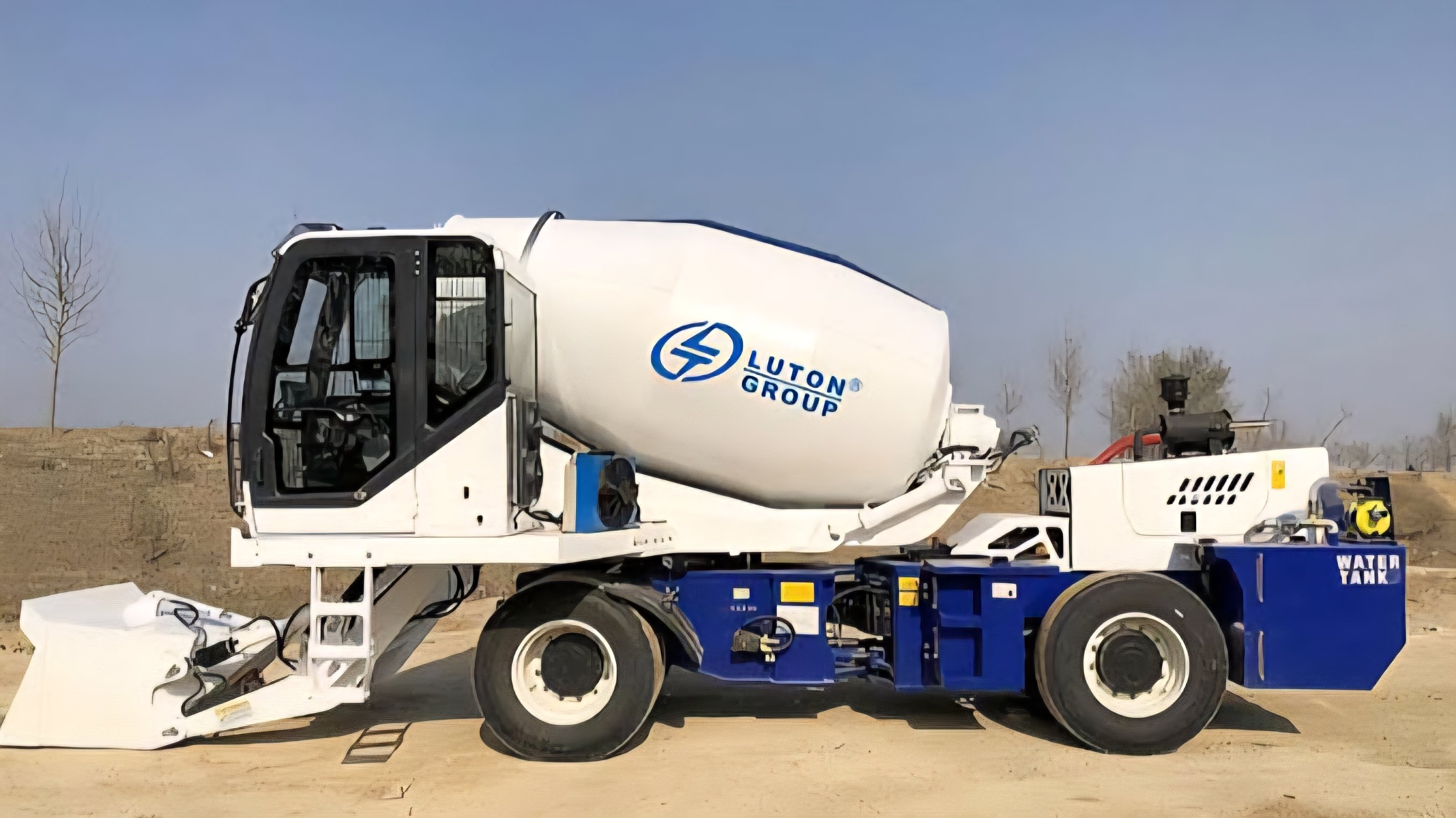 A blue and white Luton LT-1.2 self-loading concrete mixer parked on a flat surface, showing the front loading bucket, mixing drum, and heavy-duty tires.