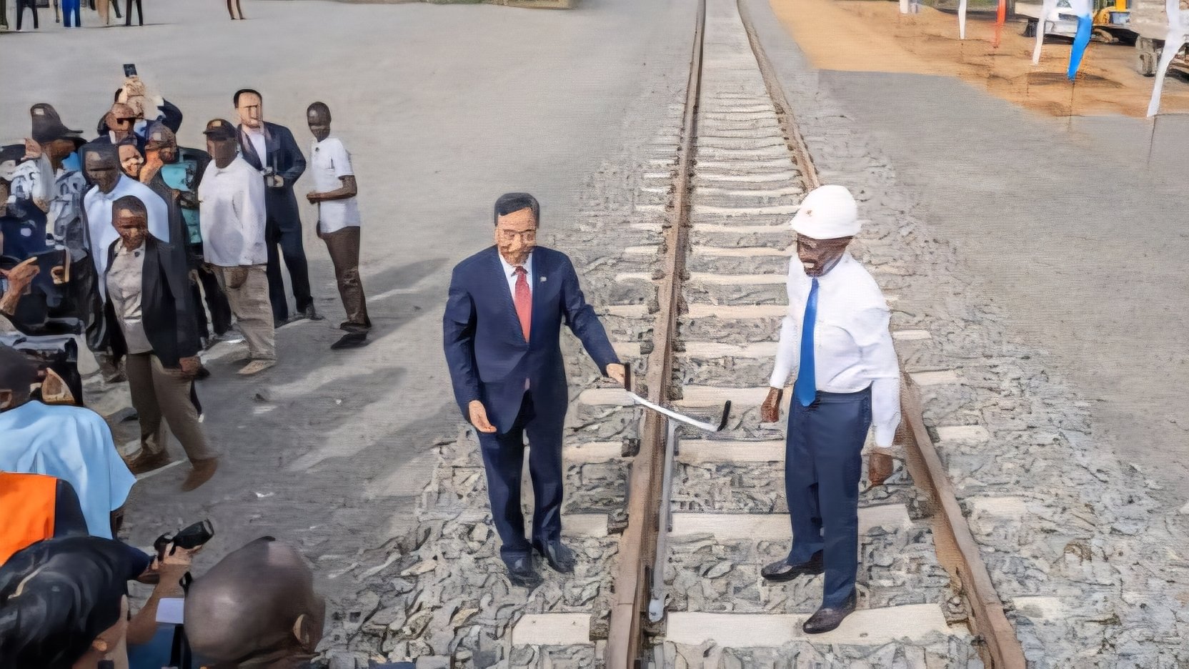 A wide-angle view of a modern railway construction site in a rural Kenyan landscape, showing heavy earthmoving equipment and initial track-bed preparation for the SGR extension.