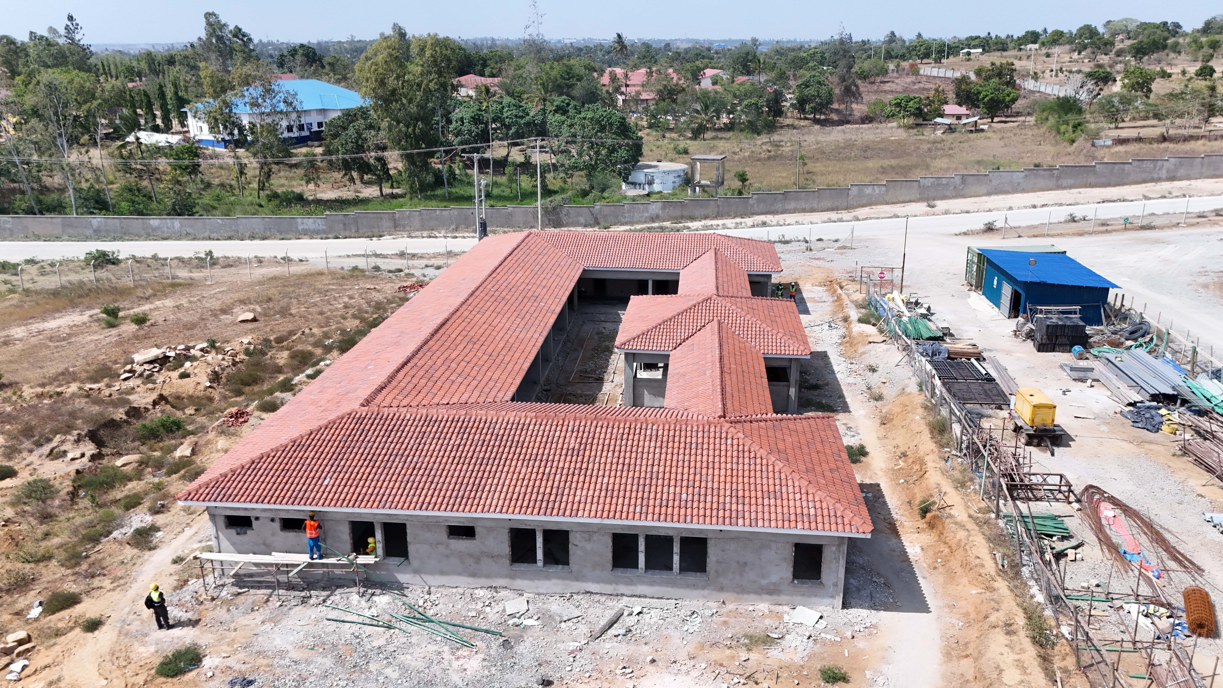 A newly constructed police post building and a renovated medical clinic standing near the construction perimeter of the Mwache Multipurpose Dam in Kwale County.