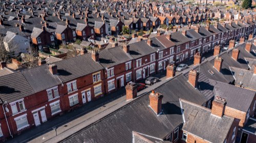 Row of social housing terraced homes in the UK under a bright summer sky.