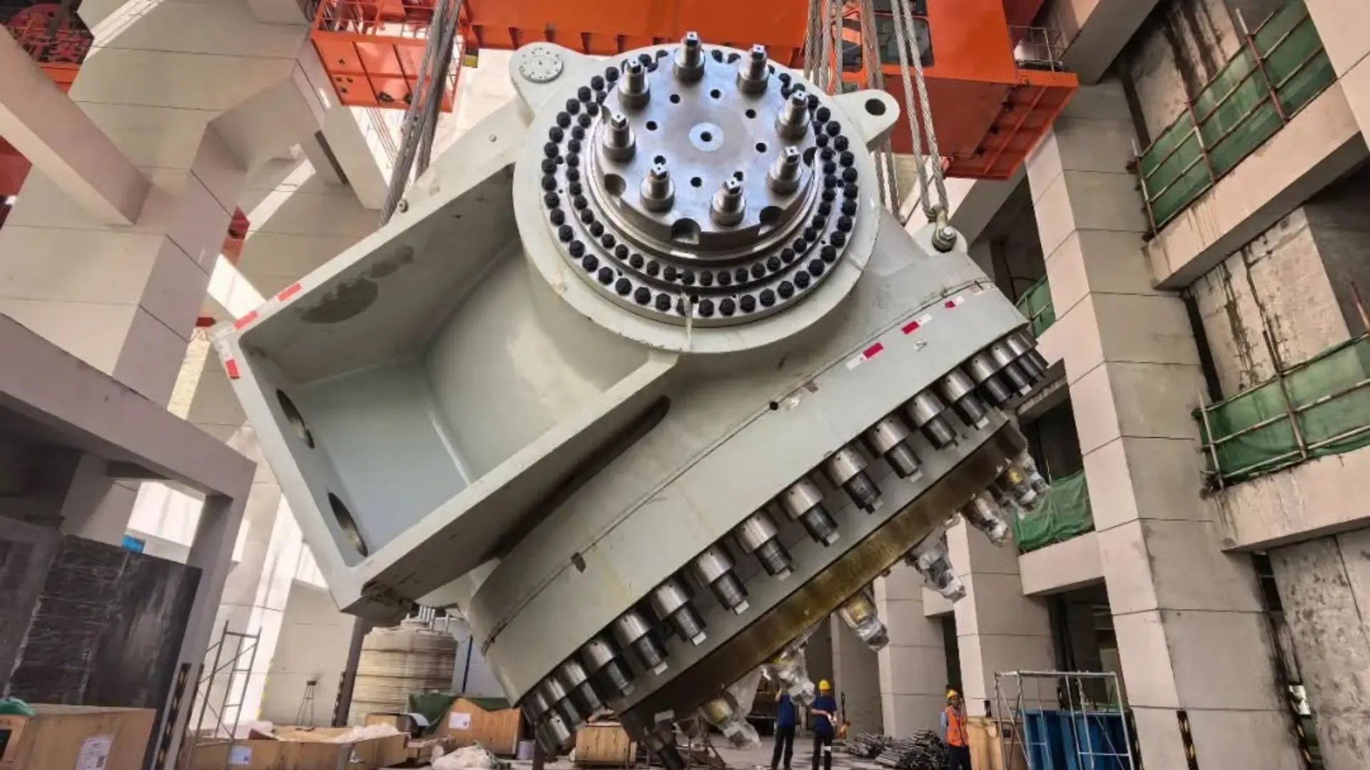 Large grey steel inlet spherical valve mounted on heavy construction supports inside an open installation bay at a hydropower construction site in Xizang.