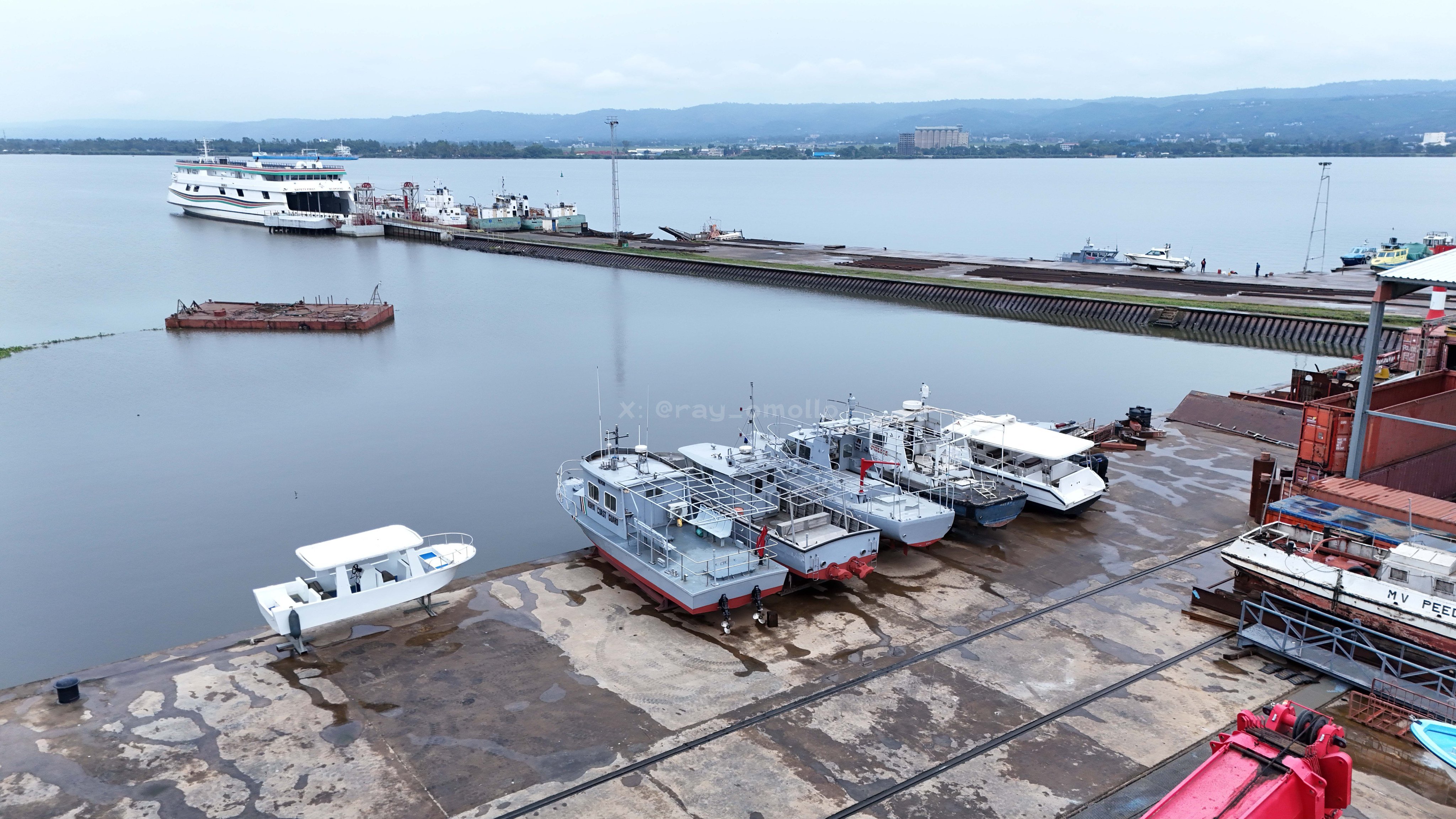 Wide-angle view of a large steel ferry hull under construction inside a dry dock at Kisumu Shipyard, featuring scaffolding and red primer paint.