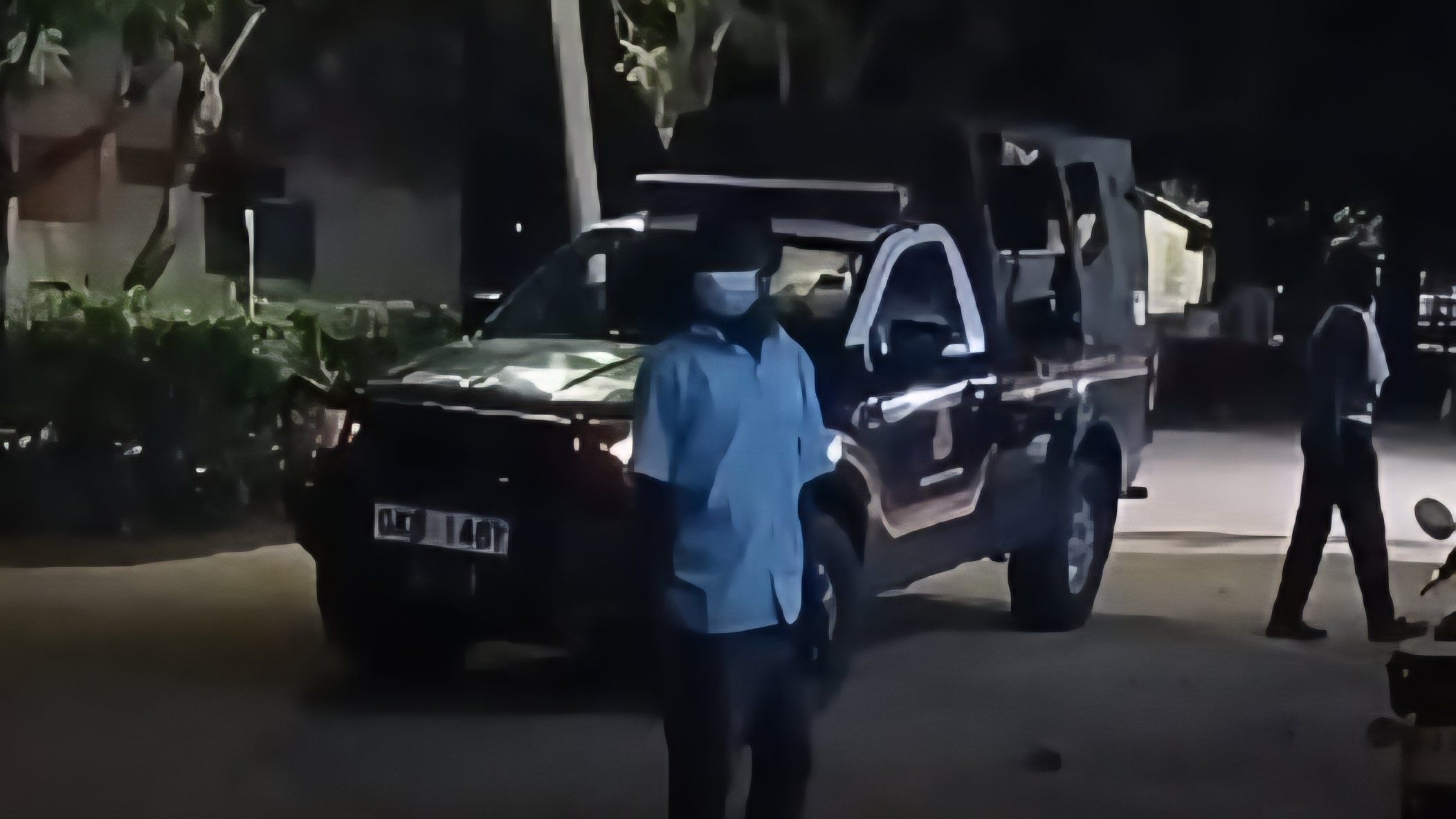 A Kenya Police Service patrol vehicle parked at night outside a building with a security officer standing nearby during an emergency response.