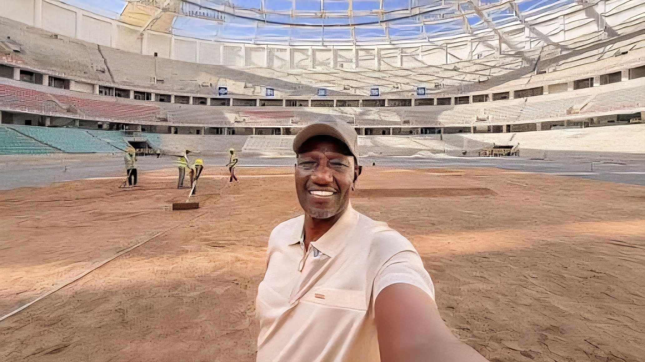 Interior view of a large modern circular stadium in Kenya featuring decorative panels with the Kenyan flag shield design under a clear sky.