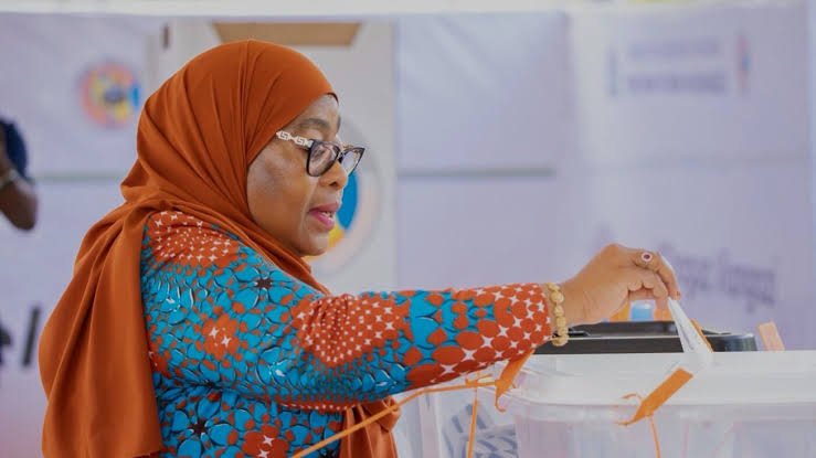 Screenshot from file 291709.png showing a digital news broadcast image of President Samia Suluhu Hassan of Tanzania speaking at a red podium.