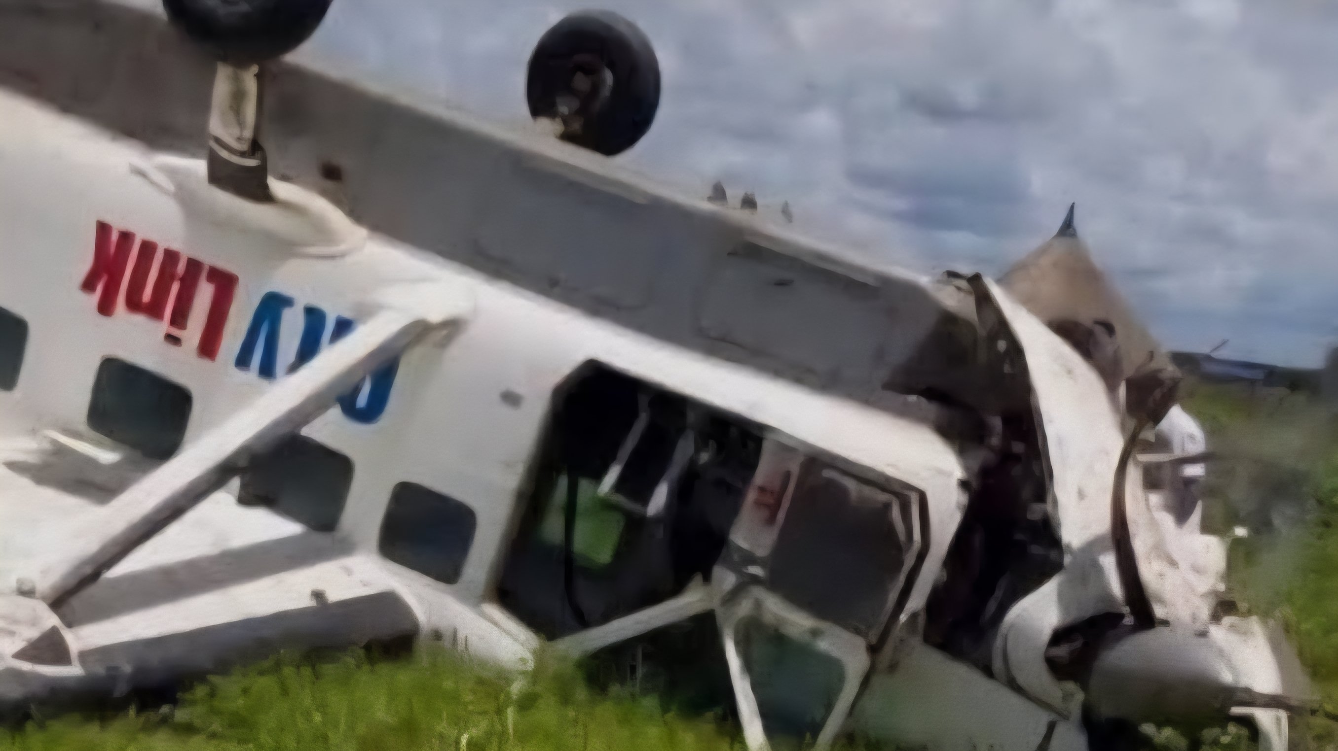 Aerial view of aircraft wreckage scattered across a rocky, mountainous terrain in South Sudan with emergency responders visible near the debris.