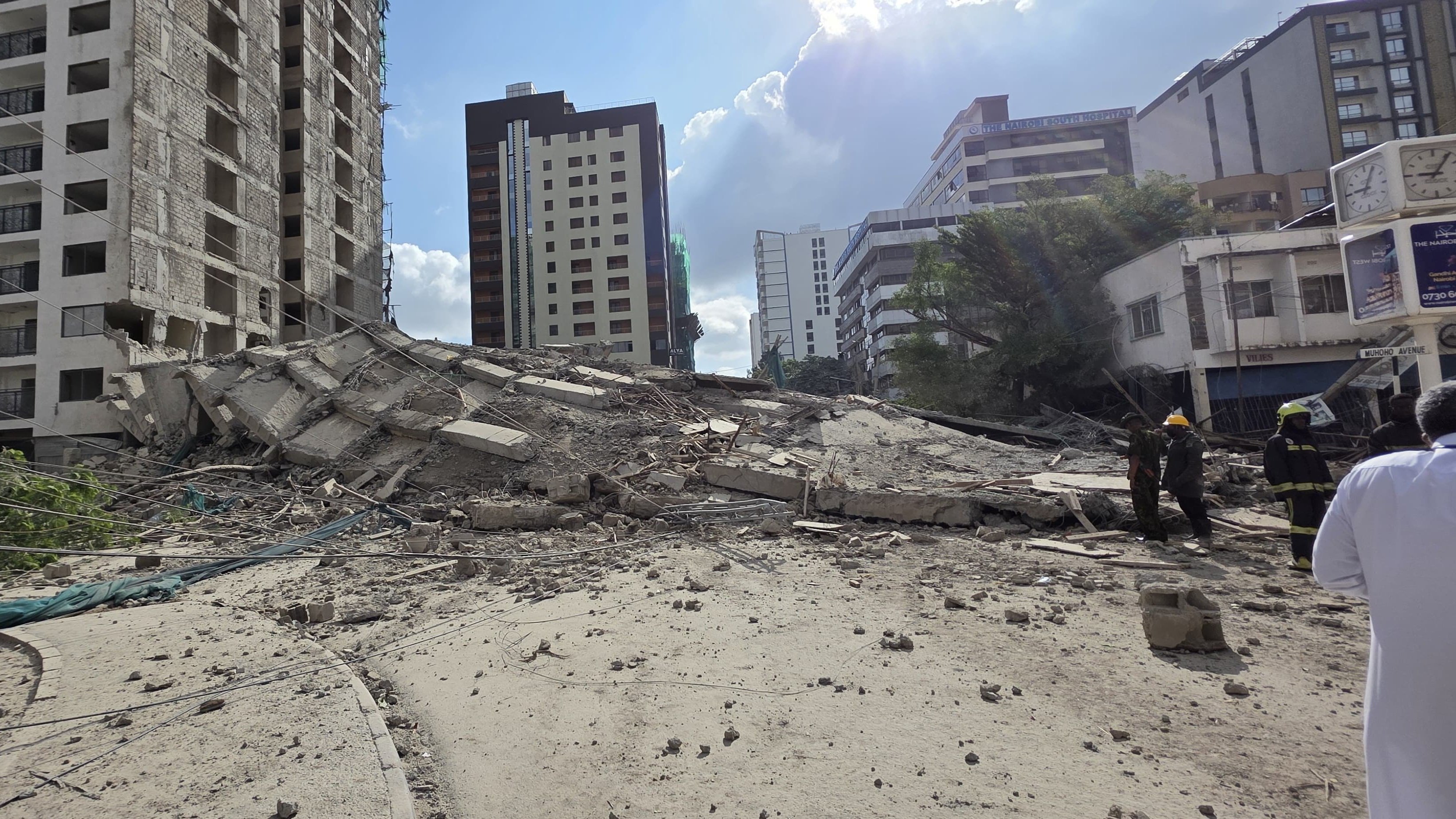 Local residents stand near the debris of a collapsed five-storey residential building in South C, Nairobi.