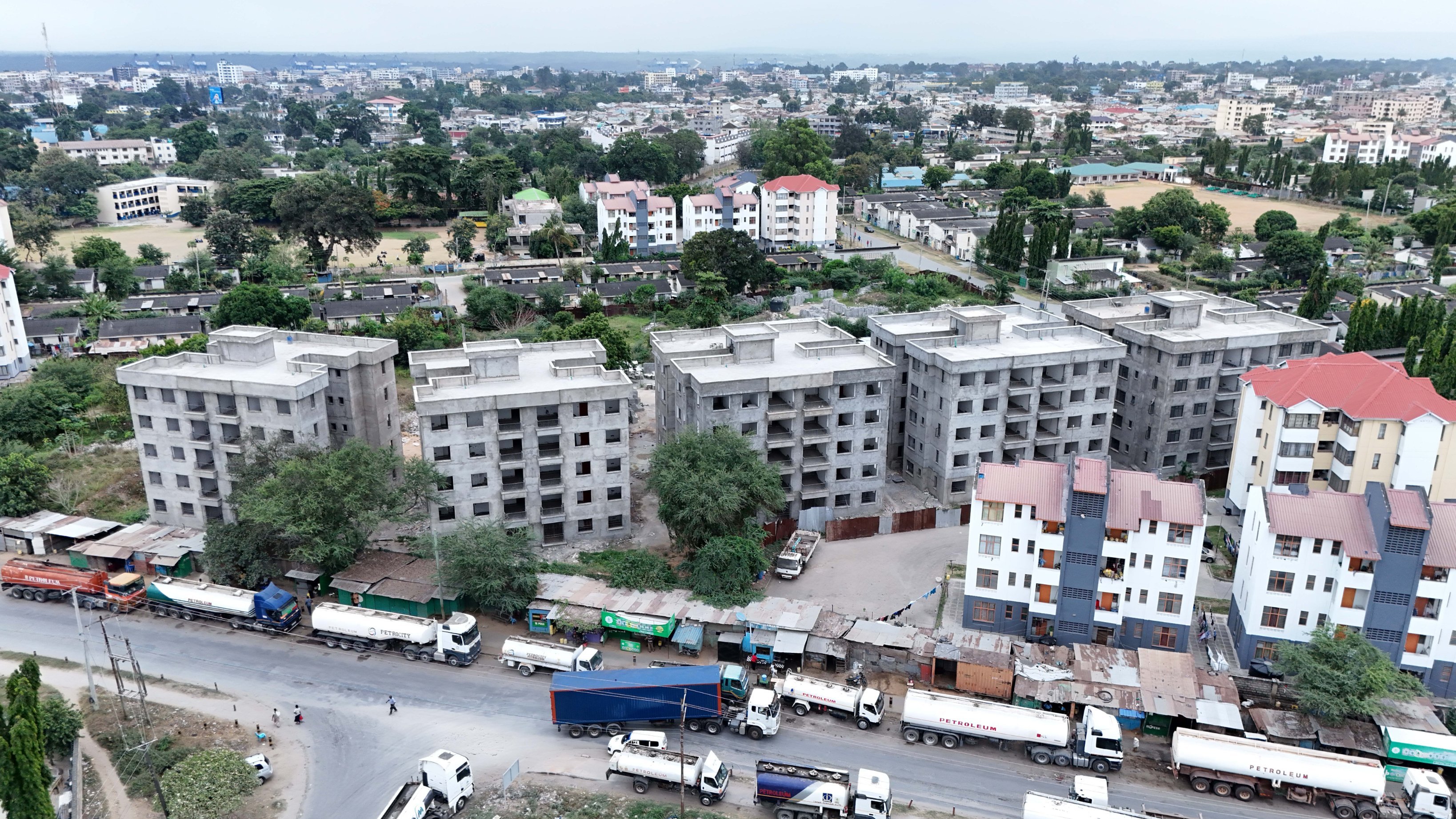A row of five-storey residential apartment blocks under construction in Changamwe, Mombasa, showing structural completion and ongoing window installations.