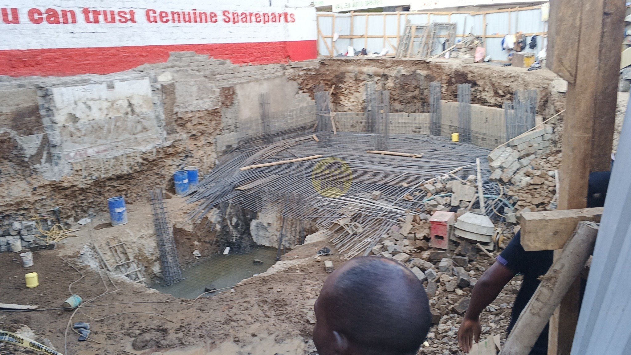 Deep excavation pit at Nairobi construction site showing rebar foundation cage and surrounding shoring walls after partial collapse.