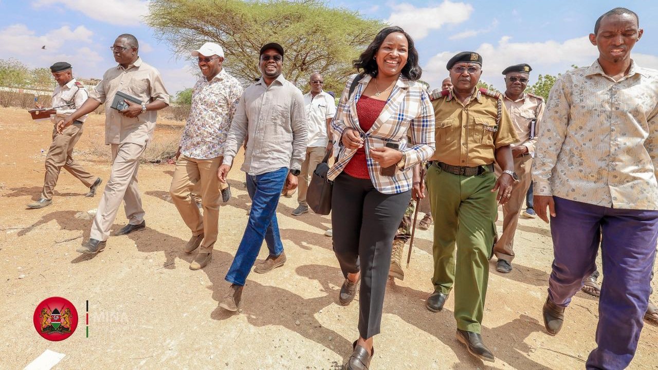 A group of government officials and security personnel walking across a dusty construction site in Wajir during a project inspection.