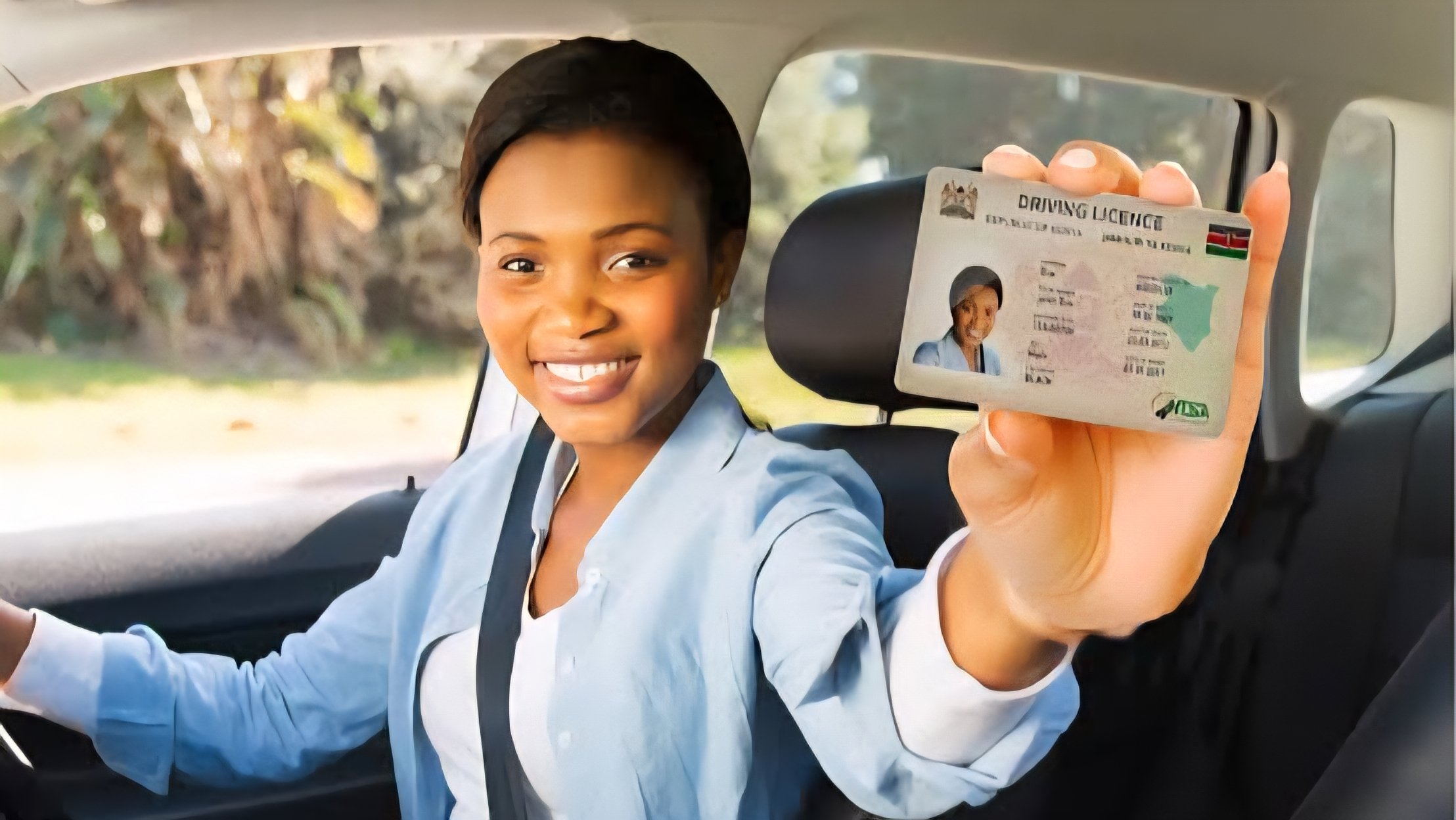 A smiling woman inside a car holding up a Kenyan second-generation smart driving license.
