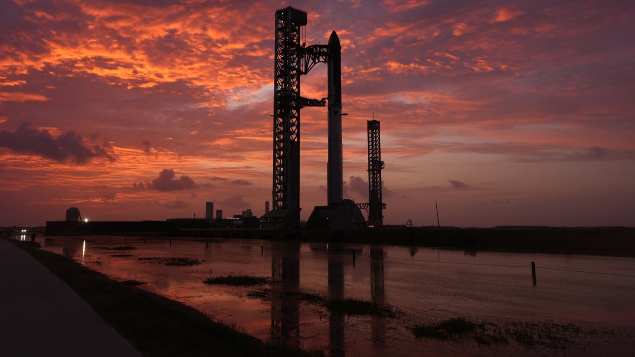 SpaceX Starship rocket mounted on launch pad at sunset during pre-launch preparations.