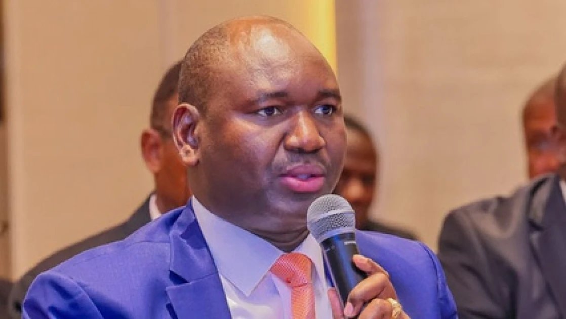 Close-up of Basic Education Principal Secretary Julius Bitok speaking into a microphone during a parliamentary committee hearing in Nairobi.