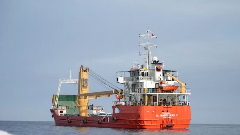 Red cargo vessel navigating through water near the Strait of Hormuz.
