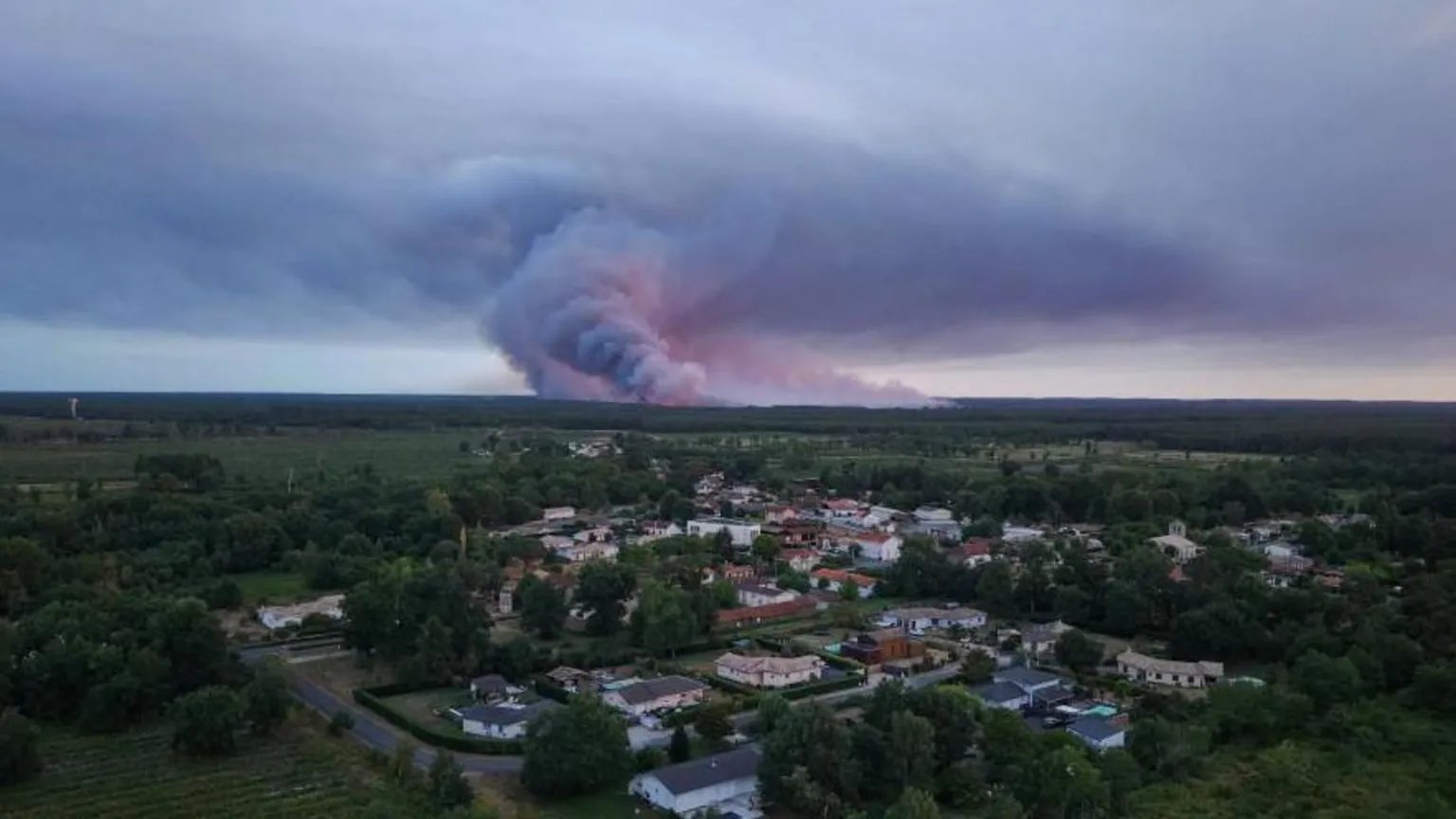 A massive pyrocumulonimbus cloud of dark smoke and ash rises over a dense pine forest in Gironde, France.