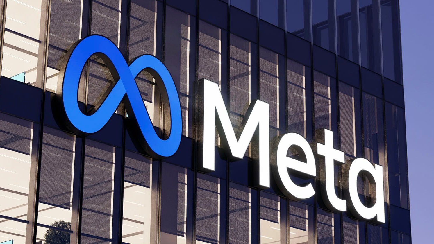 A close-up of the Meta logo on a glass and steel corporate office building reflecting the bright morning sky.